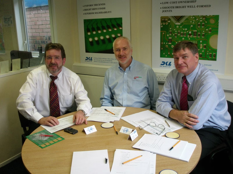 Colin Longworth sitting at a conference table, smiling and engaging in a meeting with several work colleagues